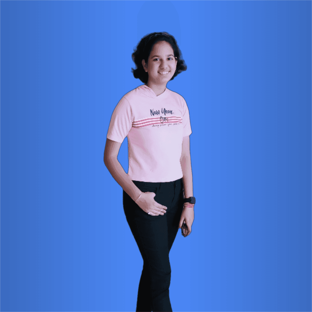 Person wearing a pink t-shirt and black pants, standing and smiling against a blue background.