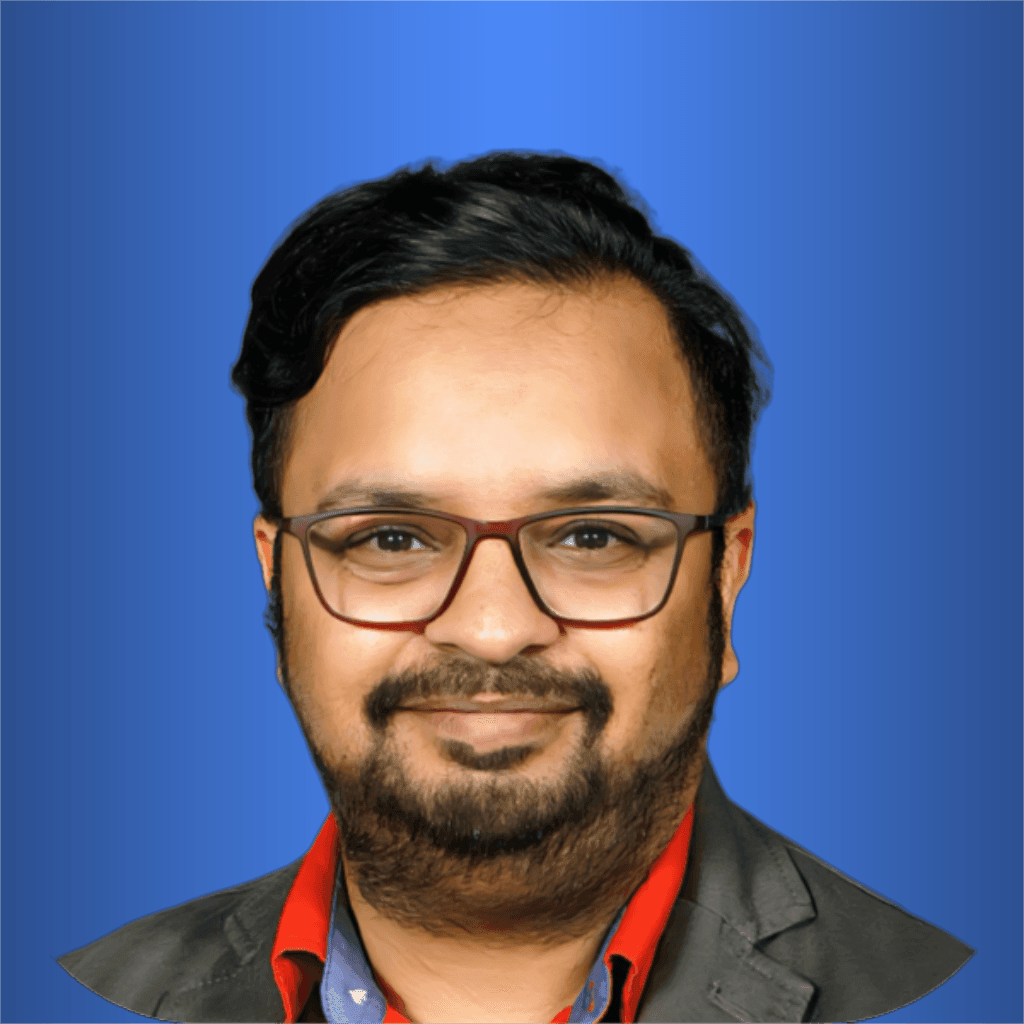 Individual wearing a red shirt with a black blazer in a portrait against a blue background.