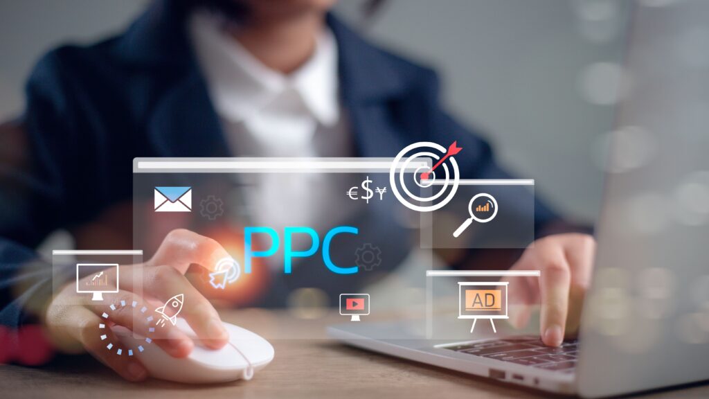 Hands on a laptop with floating PPC interface icons: blue PPC text, target bullseye, envelope, chart, magnifier, ad window, and currency symbols.