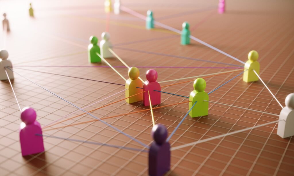 Colorful peg figures linked by multicolored strings across a grid, illustrating a connected network.